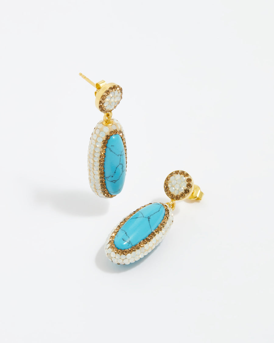  product shot of turquoise gemstone long oval earrings surrounded by white crystals on a white background