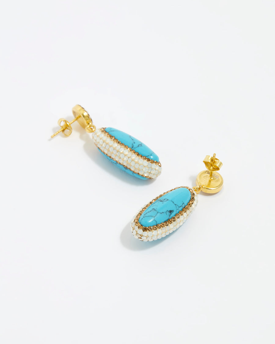 Soru Jewellery product shot of turquoise gemstone long oval earrings surrounded by white crystals on a white background