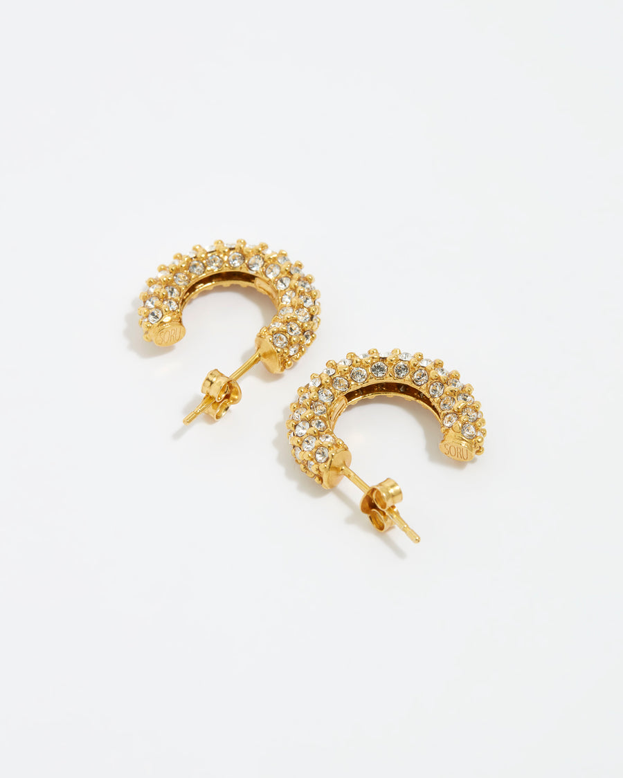 close up image shot of small crystal embellished hoop earrings lying flat on a white background