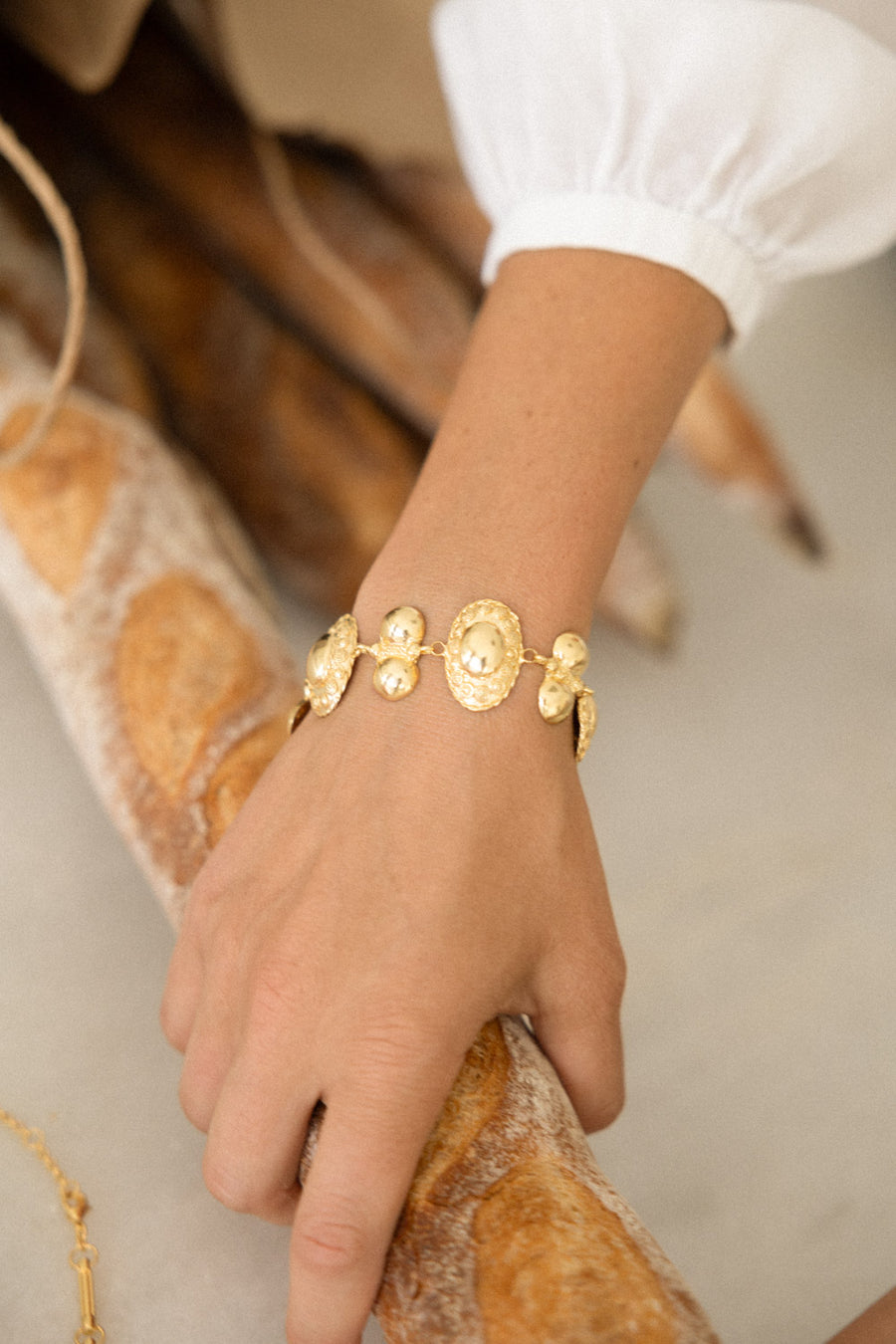 Image showing Daphne Oz wearing the gold bracelet holding a baguette bread stick