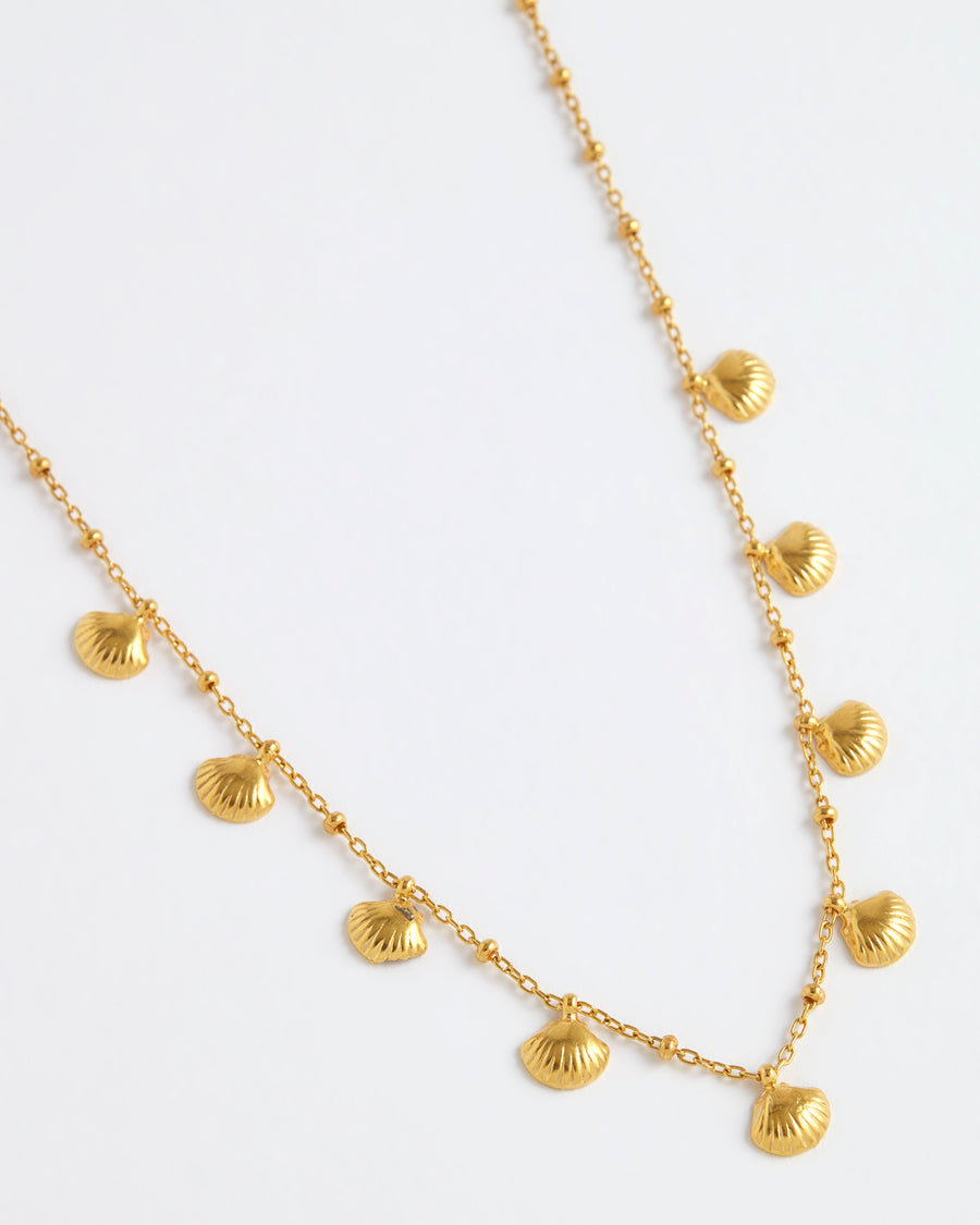 product shot of yellow gold plated necklace with mini shells attached around the necklace on white background