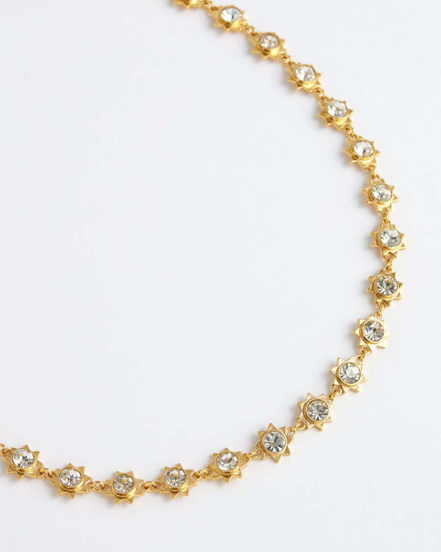 Close up front view image shot of gold star necklace with large crystal embellishments on each star on a white background