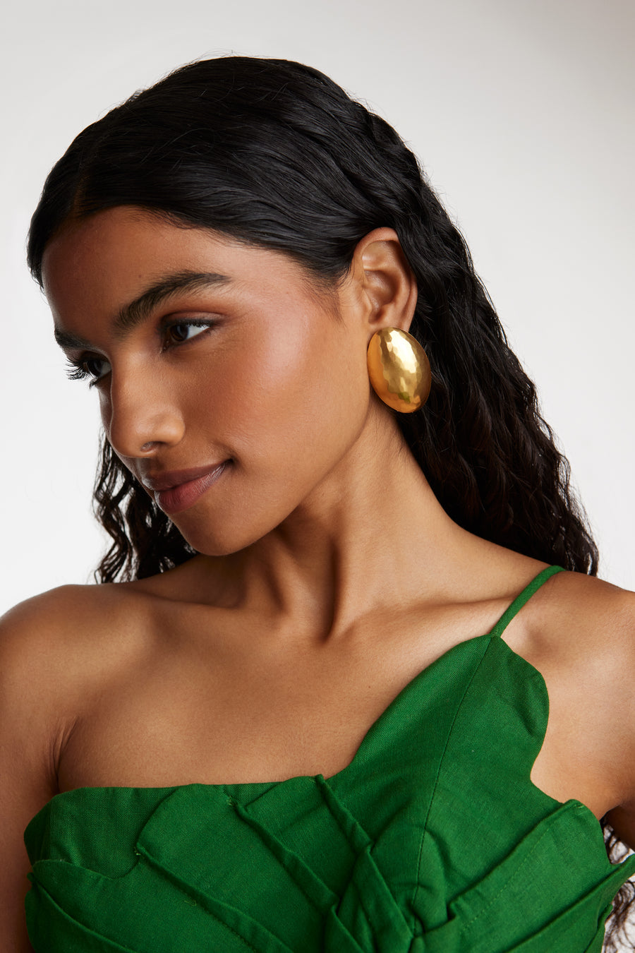 side view model shot wearing the Soru Jewellery gold oversized textured oval earrings while model is smiling