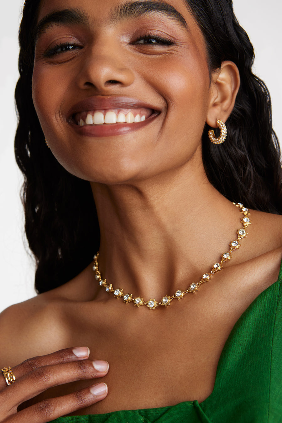 model shot wearing small crystal embellished hoop earrings, gold ring and gold crystal necklace 