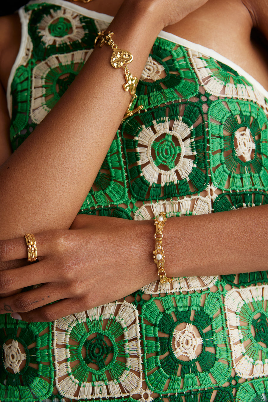 Close up model shot wearing bracelet with textured bar and pearls and also a chunky gold bracelet with a gold ring