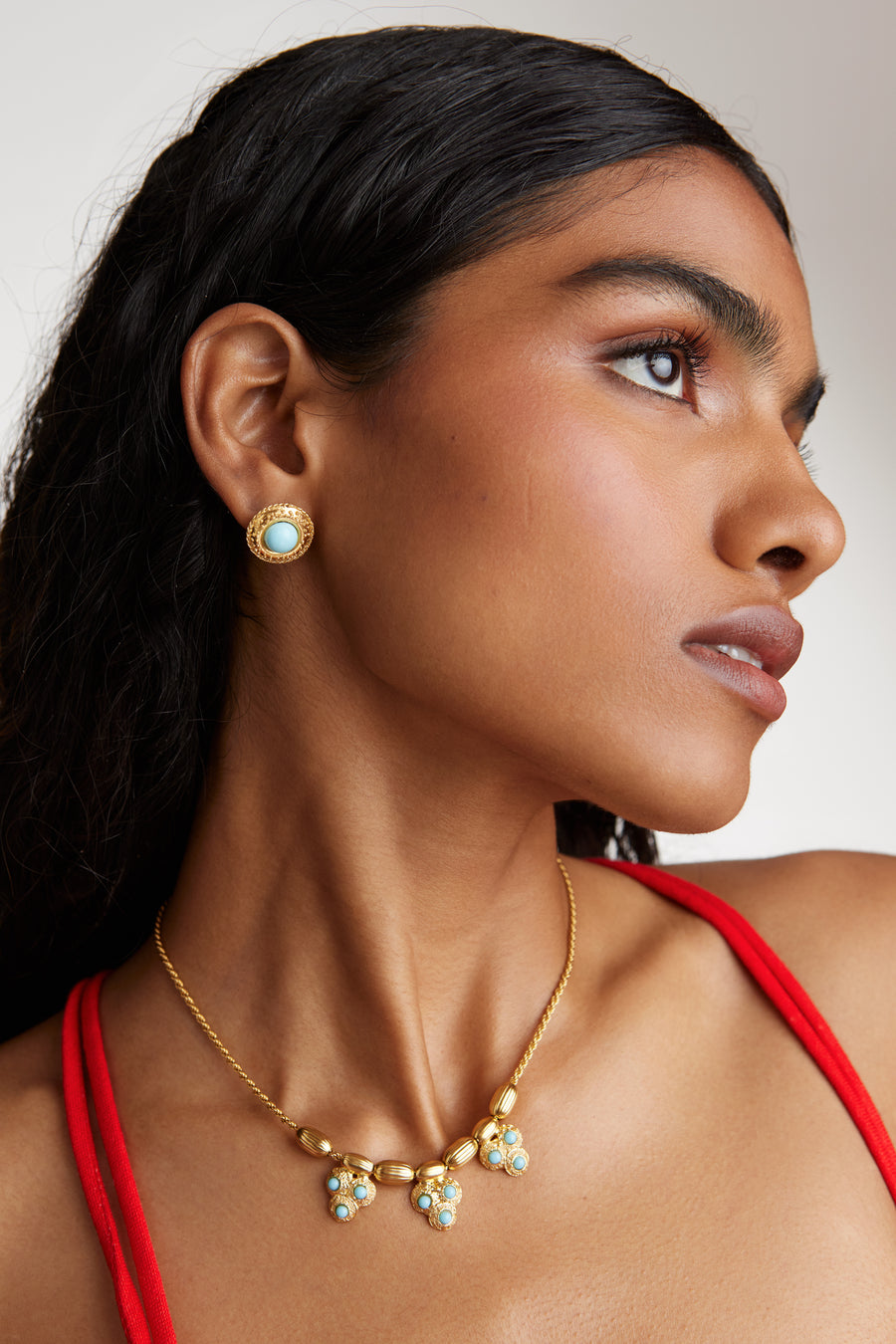 Side view of model shot wearing the Soru Jewellery round turquoise textured stud earrings and matching turquoise beaded necklace.