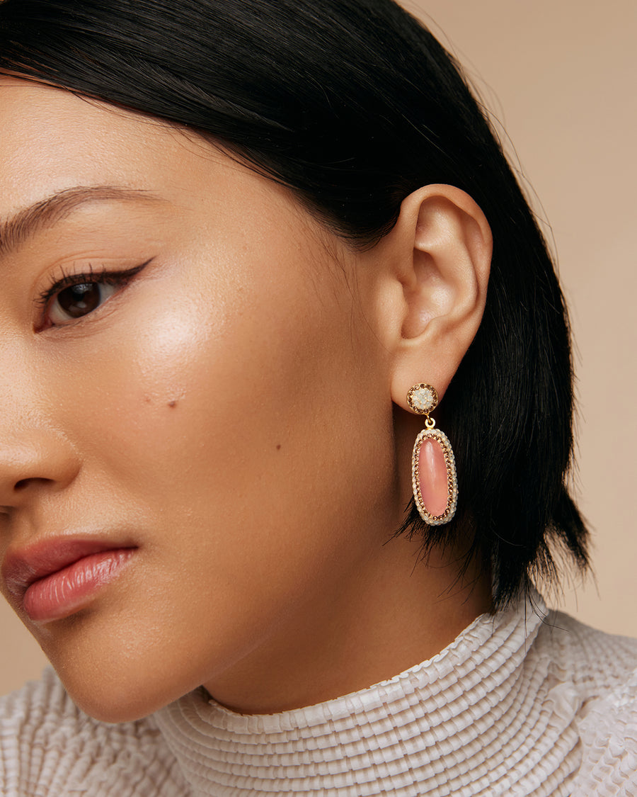 model shot of pink rose quarts long oval earrings surrounded by white crystals